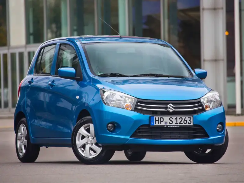 Niebieski Suzuki Celerio stoi przed nowoczesnym budynkiem.