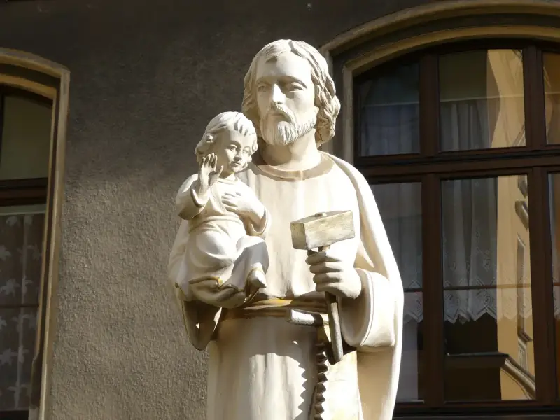 Święty Józef z Dzieciątkiem Jezus, trzymający młotek i piłę, symbolizujący, że Jezus był cieślą.