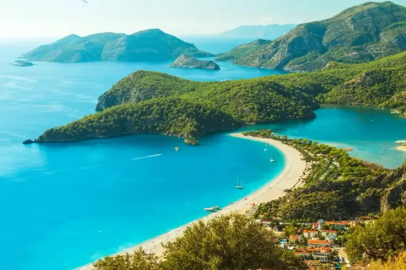 Turcja zachwyca turkusowym morzem i zielonymi wzgórzami. Widok na zatokę z plażą i górami.