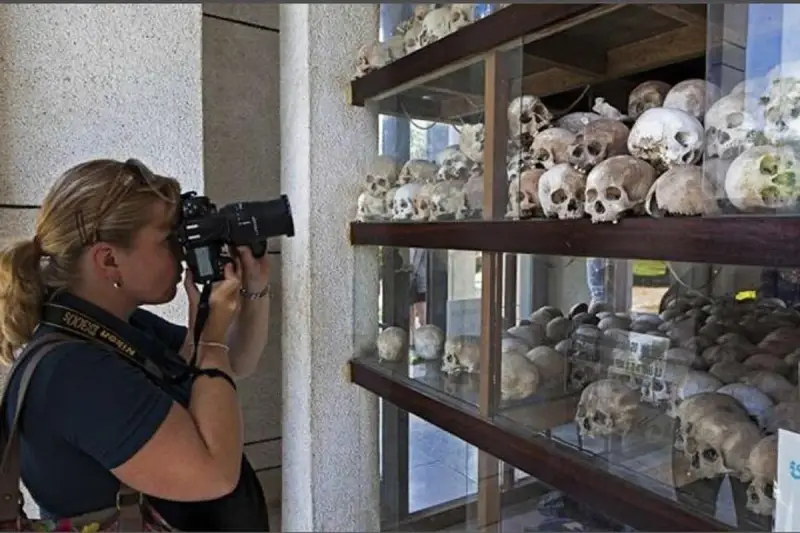 Kobieta fotografuje ludzkie czaszki na wystawie upamiętniającej pola śmierci w Kambodży.