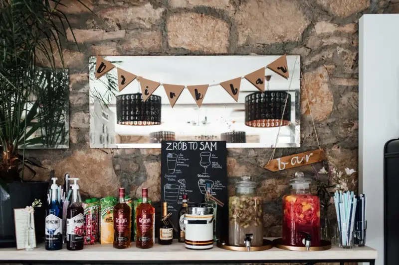 Stół z butelkami alkoholu, sokami i dzbankami z owocami, gotowy na drinki na wesele.