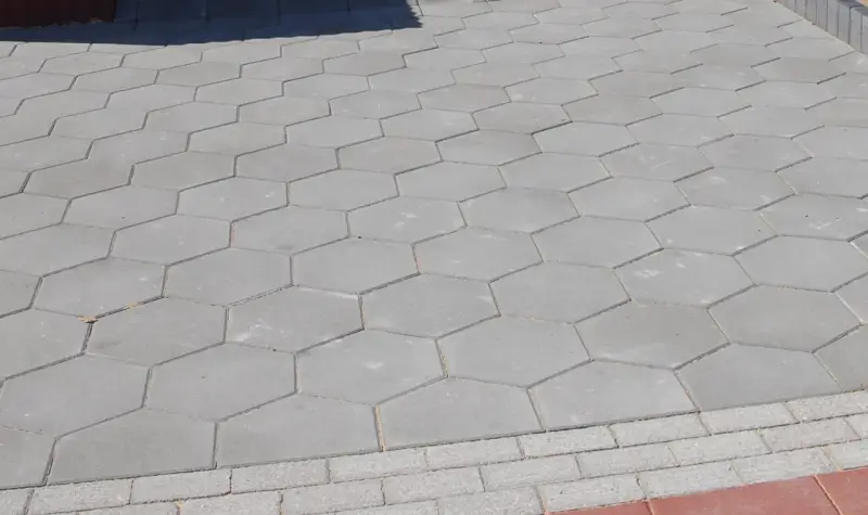 Szara, sześciokątna trelinka tworzy wzór na chodniku.