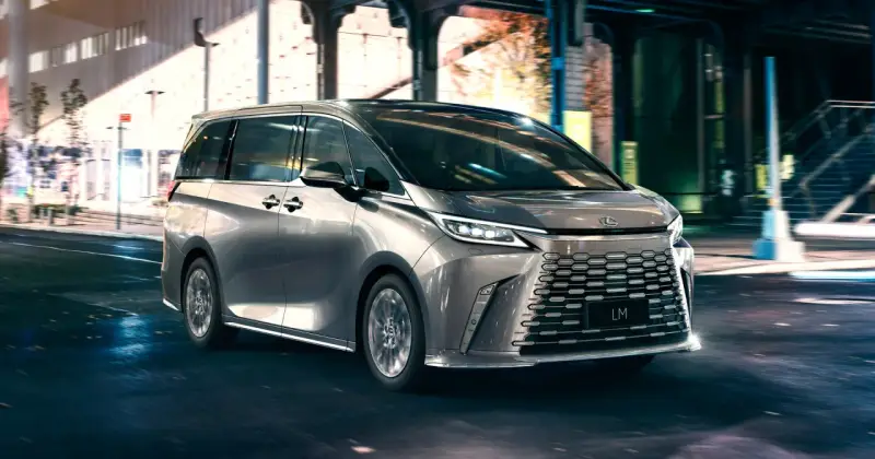 Srebrny van Lexus LM 350h na nocnej ulicy z rozmytym tłem.