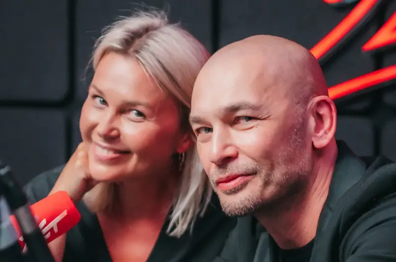 Tomasz Wygoda z żoną i dziećmi, uśmiechnięci przed mikrofonem.
