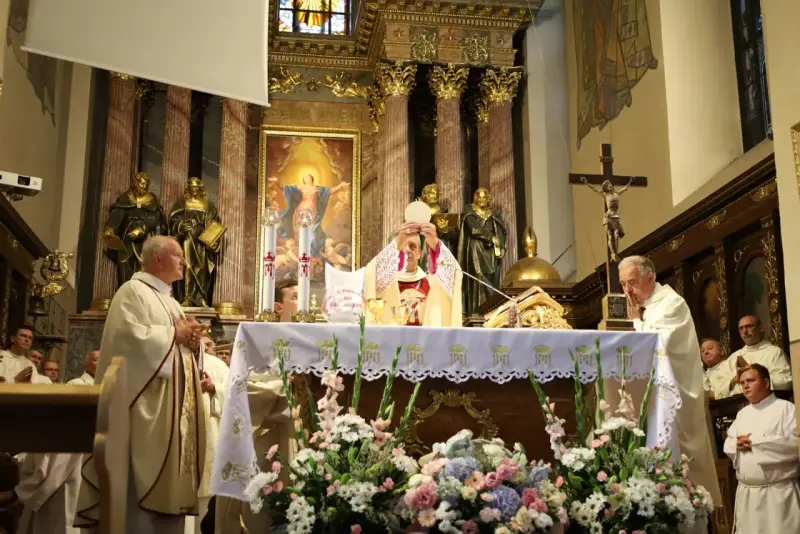 Uroczysta msza święta w kościele. Kapłan podnosi hostię, symbolizując piękna modlitwę do Boga. W tle złote zdobienia i obrazy.