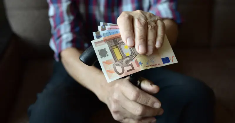 Dłoń trzyma banknoty euro, które są walutą Słowenii.