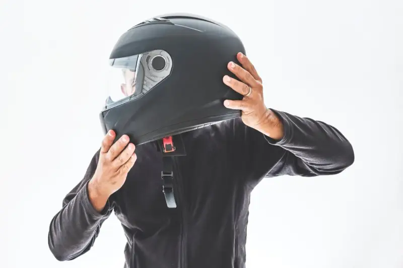 Persona indossa un casco integrale nero, pronto per un giro in moto.