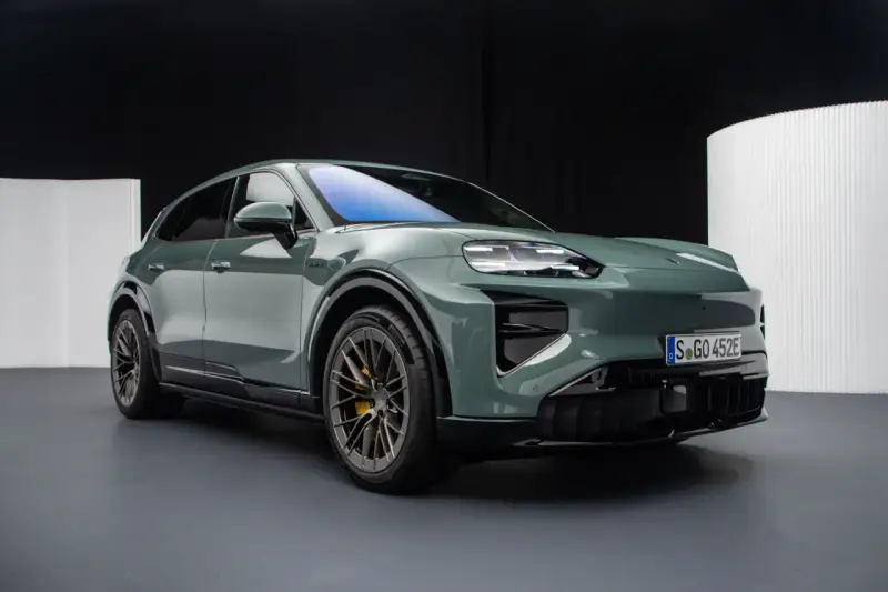 Zielony elektryczny Porsche Macan na ciemnym tle.