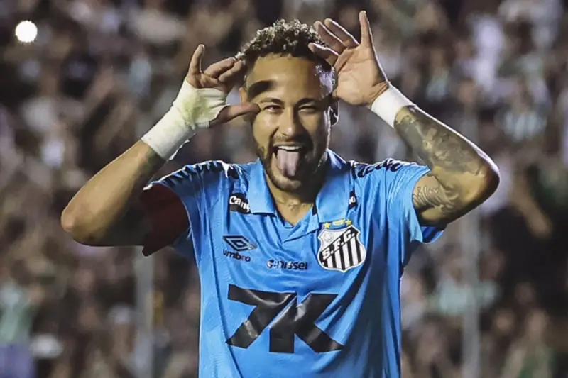 Neymar w niebieskiej koszulce Santos z charakterystycznym gestem i wystawionym językiem. Tak wygląda boisko, gdzie gra Neymar.