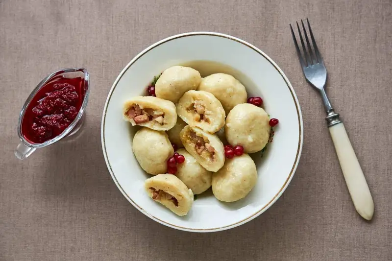 En skål med kroppkakor, en klassisk svensk rätt, serveras med lingonsylt. Recept på kroppkakor finns här.