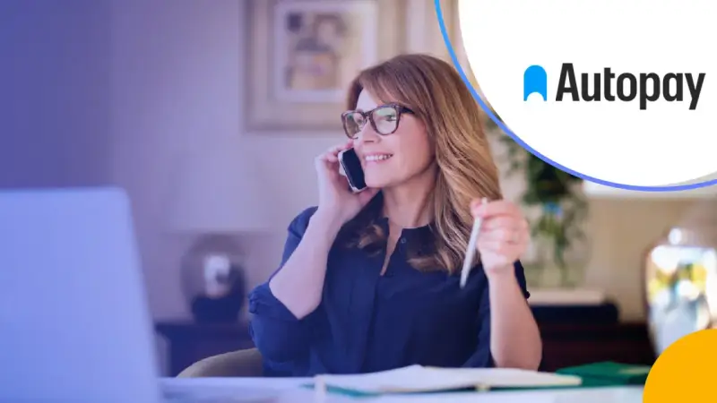 Kobieta rozmawia przez telefon, trzymając długopis. Logo Autopay obok. Dowiedz się, autopay co to jest.
