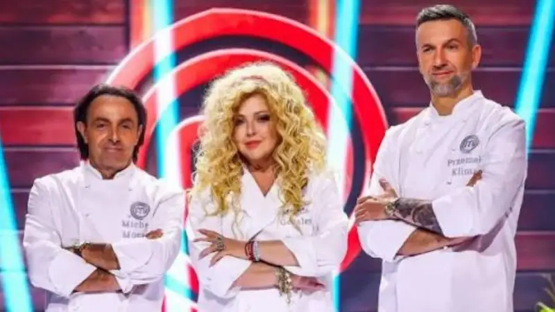 Trzech jurorów MasterChef: Michel Moran, Magda Gessler i Przemysław Klimsa, w białych fartuchach, z rękami skrzyżowanymi na piersi.