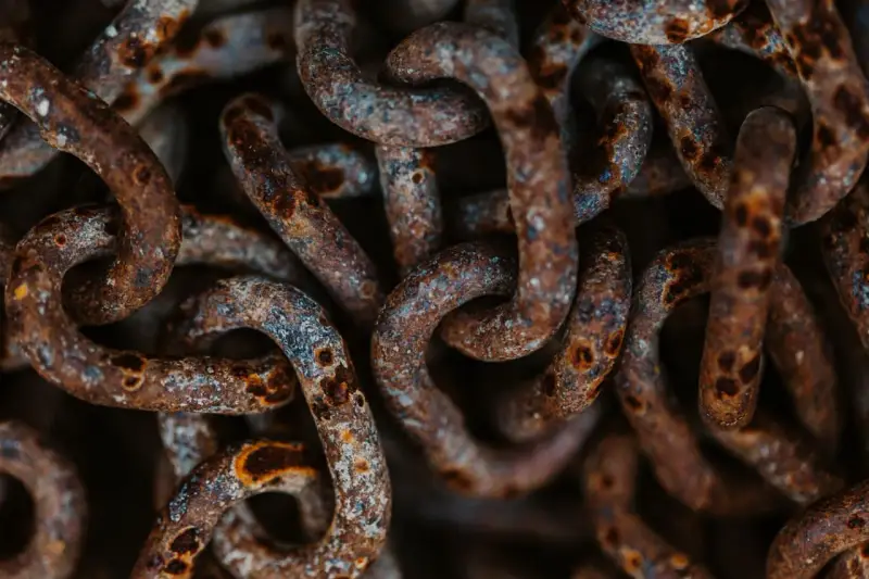 Dettaglio di una catena di ferro arrugginita, con macchie di ossido marrone e grigio. Utile per capire come togliere la ruggine da una catena di ferro.