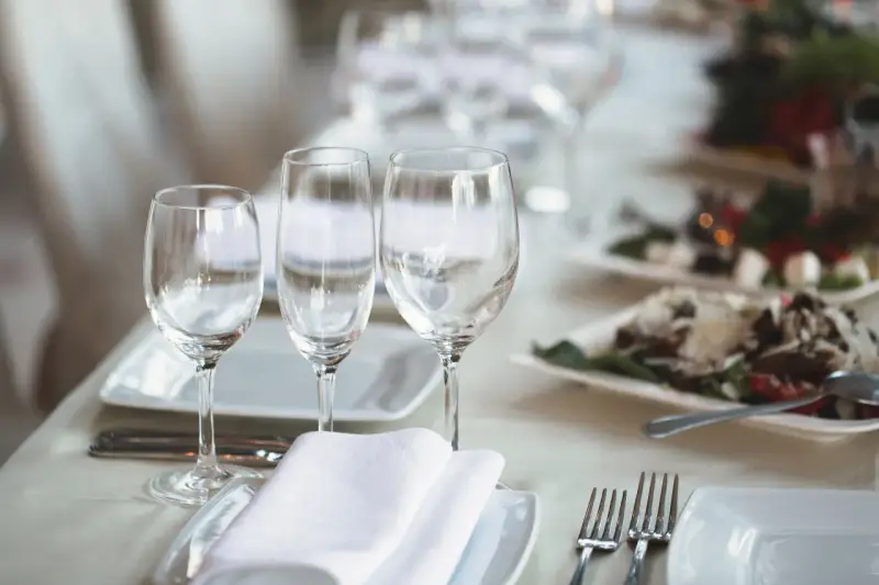 Trois verres à eau sont disposés sur une table dressée, prêts pour un repas.