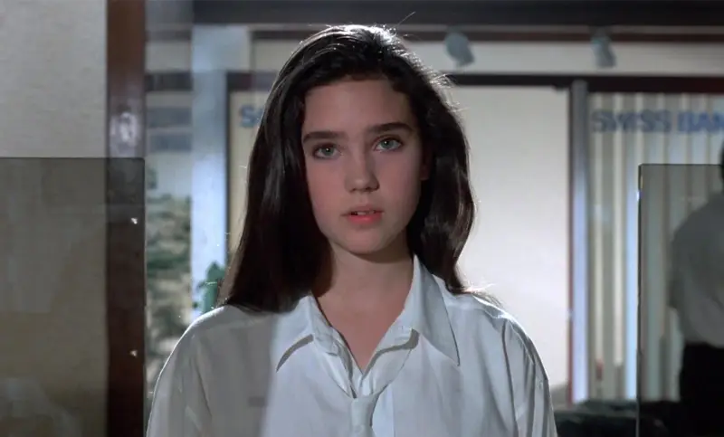 Młoda Jennifer Connelly w białej koszuli, z charakterystycznym spojrzeniem, jak z jej wczesnych filmów.