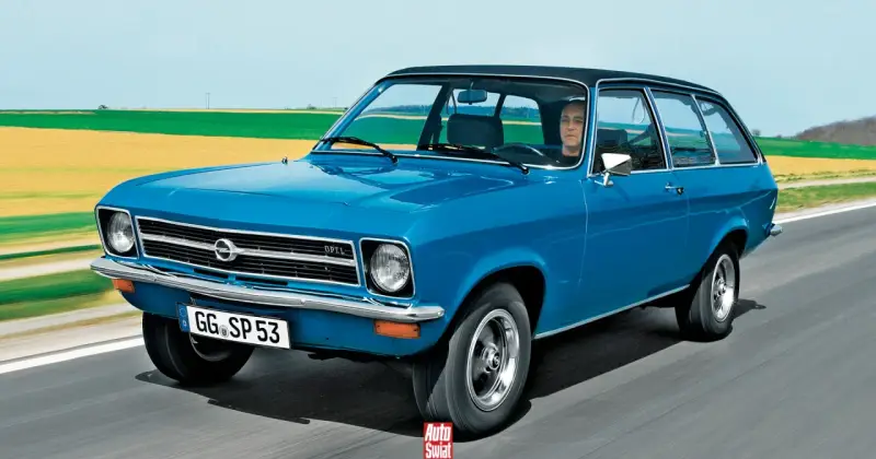 Niebieski Opel Ascona w wersji kombi jedzie po drodze, za nim pola i niebo.