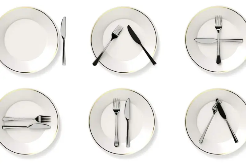 Six assiettes blanches avec des couverts disposés de différentes manières, illustrant la position des couverts signification.