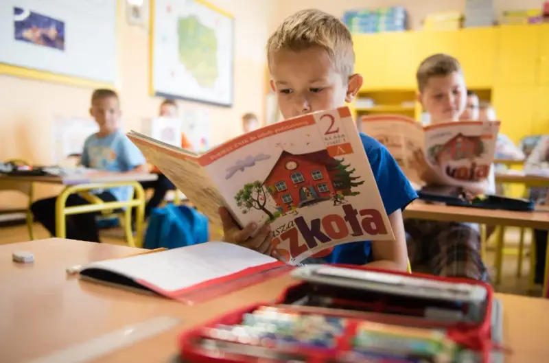 Chłopiec z zapałem czyta podręcznik "Nasza Szkoła". To dobry start dla każdego ucznia, by z radością poznawać świat.