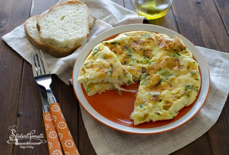 Deliziosa frittata di albumi con erbe aromatiche, servita su un piatto arancione con pane tostato e posate.
