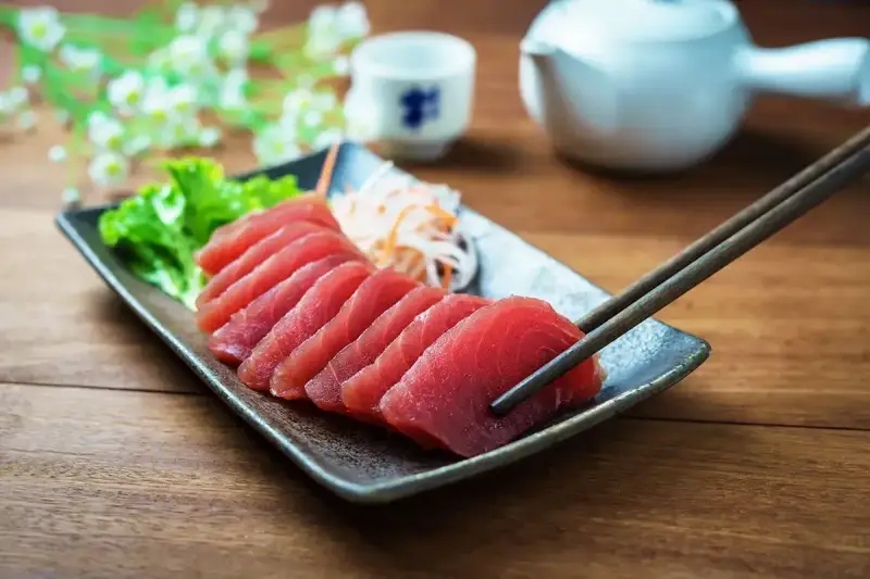 Pyszne japońskie ryby, świeże sashimi z tuńczyka, podane z sałatką i sosami. Pałeczki gotowe do degustacji.