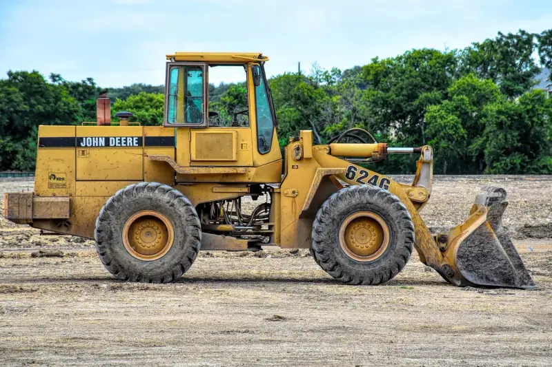 Żółta koparko-ładowarka John Deere 624G gotowa do pracy, wymaga odpowiednich uprawnień do obsługi.