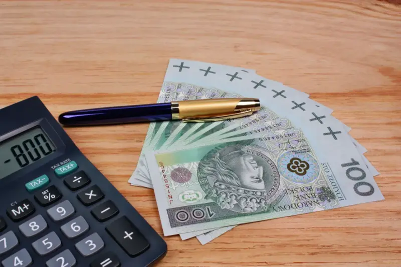 Kalkulator, długopis i banknoty 100 zł. Szukasz, który bank ma najwyższe oprocentowanie lokat na 3 miesiące?