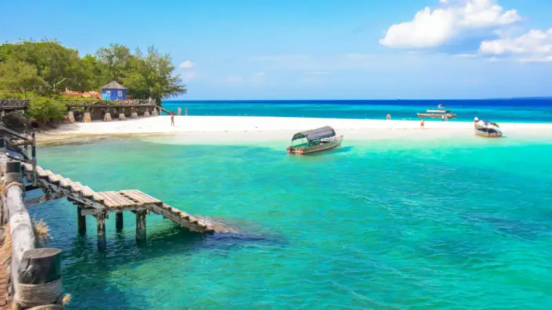 Zanzibar - wczasy opinie: turkusowa woda, biała plaża, drewniany pomost i łodzie. Rajskie widoki idealne na wakacje.