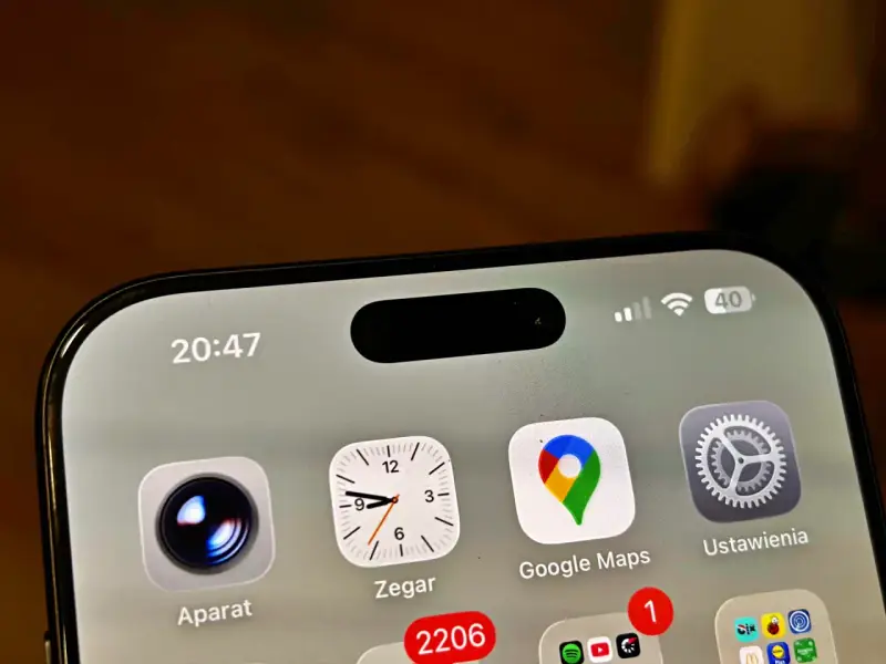 Ekran iPhone z widoczną dynamiczną wyspą, ikonami Aparat, Zegar, Google Maps i Ustawienia. Czas 20:47.