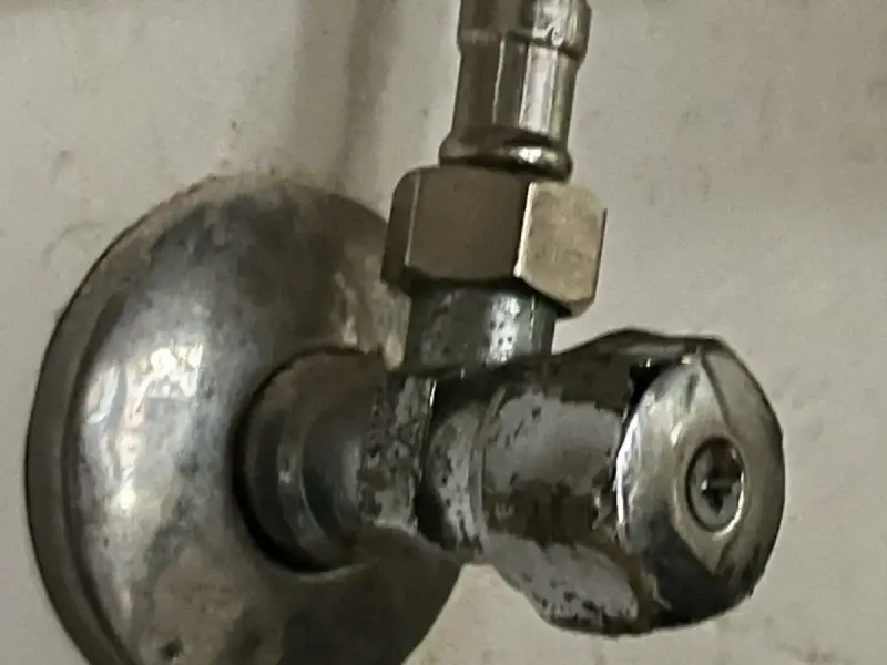 Metalowy zawór wodny, pokazujący, jak odkrecic zawor z woda. Widoczny śrubunek i pokrętło.