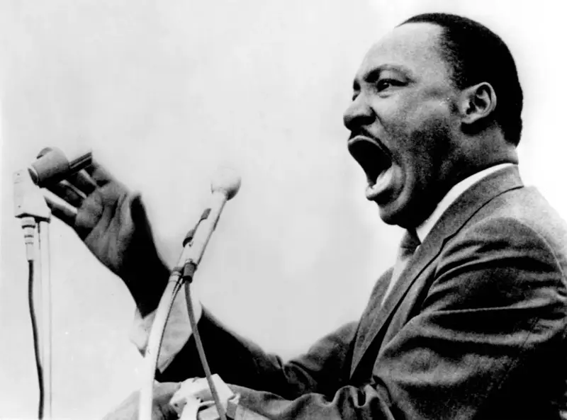 Martin Luther King przemawia z pasją do mikrofonu, jego głos niesie nadzieję i wolność.