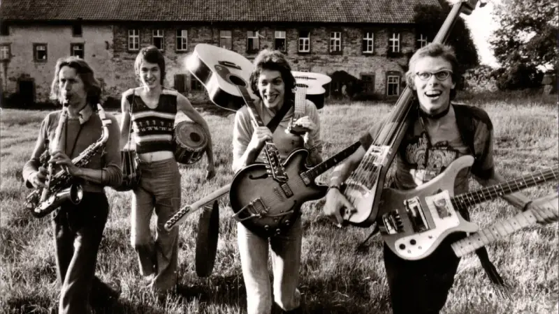 Vier Musiker mit Gitarren und Saxophon, ein Schlagzeuger. Eine Szene, die an deutsche Bands der 70er erinnert, voller Energie und Musik.