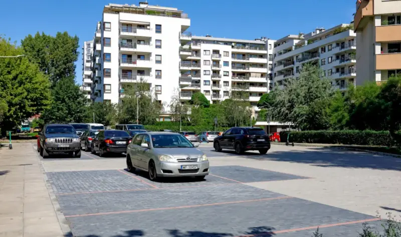 Nowoczesne osiedle w Warszawie, parking z samochodami. Zastanawiasz się, ile kosztuje kawalerka w Warszawie?