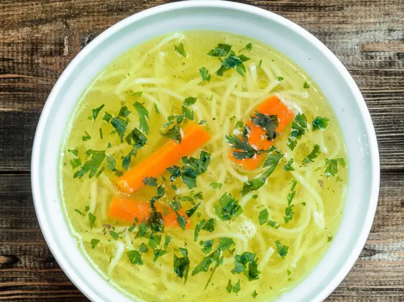 Aromaticzny rosół z makaronem, marchewką i natką pietruszki. Czy rosół ma białko? Tak, dzięki mięsu, z którego jest gotowany, dostarcza cennego białka.