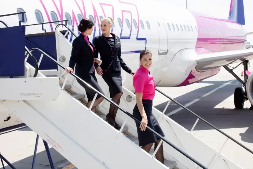 Uśmiechnięte stewardessy Wizz Air schodzą po schodkach. Ciekawe, ile zarabia stewardessa Wizz Air za taką pracę?