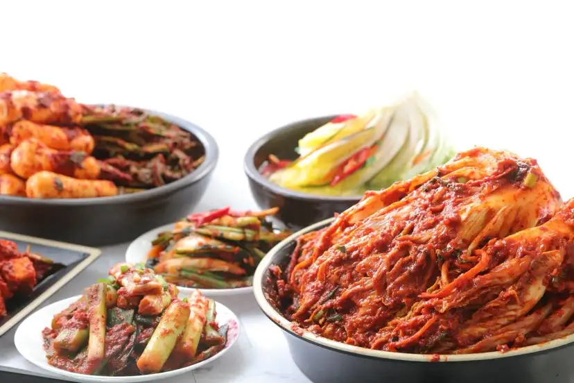 Różne rodzaje kimchi w miskach i na talerzach, w tym cała główka kapusty.