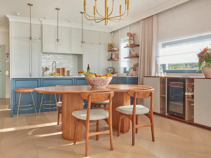 Jadalnia w stylu mid century modern z owalnym drewnianym stołem, krzesłami i wyspą kuchenną.