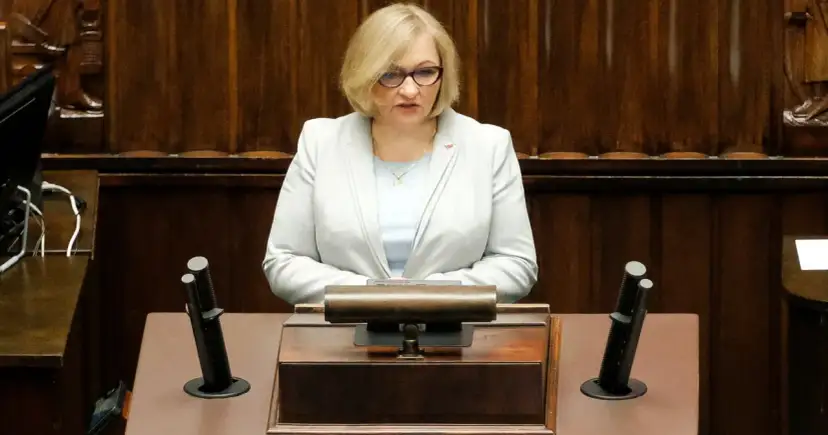 Kobieta w jasnej marynarce przemawia w sejmie, dyskutując o wpływie polityki PiS na prawa kobiet w Polsce.