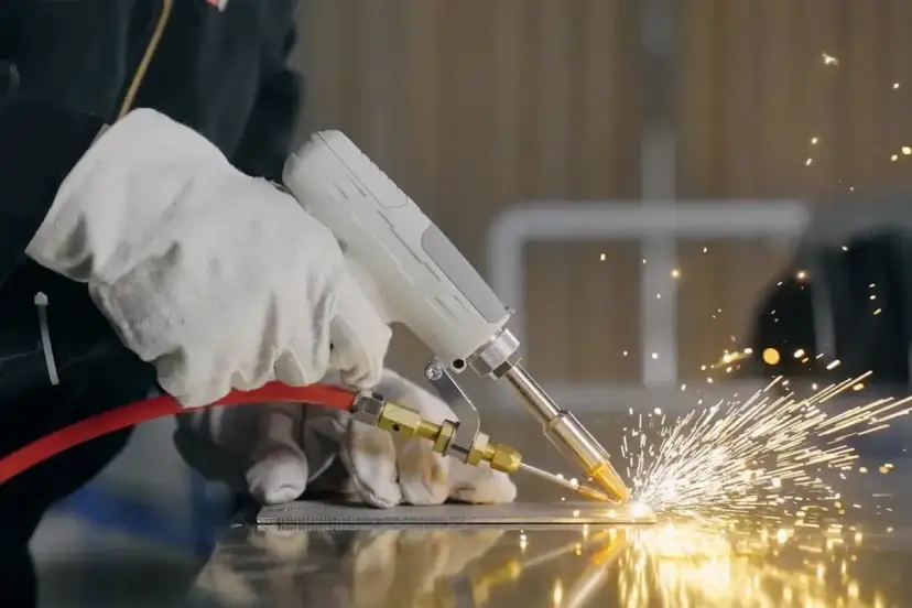 Ręce w rękawicach wykonują spawanie TIG, tworząc snop iskier na metalowej powierzchni.