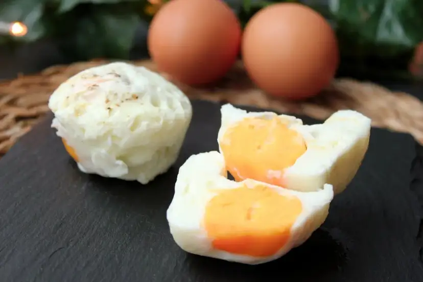 Huevos cocidos en microondas, uno entero y otro partido mostrando la yema naranja. Dos huevos enteros al fondo.