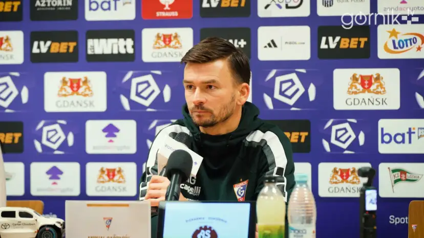 Trener rozmawia o lechia transfery. Na ścianie logo Lechii Gdańsk.