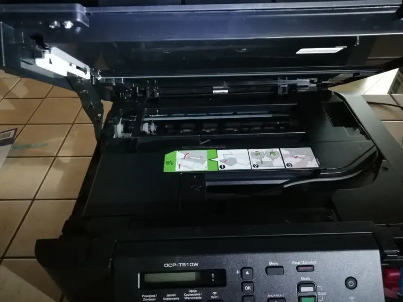 Otwarta drukarka Brother DCP-T510W z widocznymi instrukcjami i panelem sterowania.