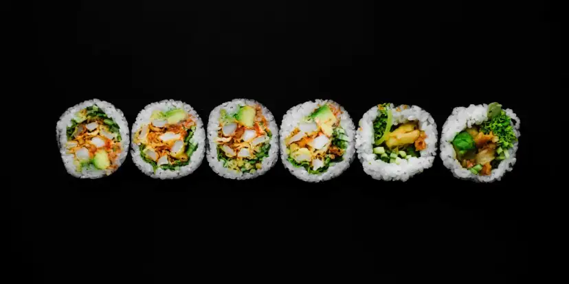Sześć kawałków futomaki, czyli dużych rolek sushi, z awokado, warzywami i smażonymi kawałkami.