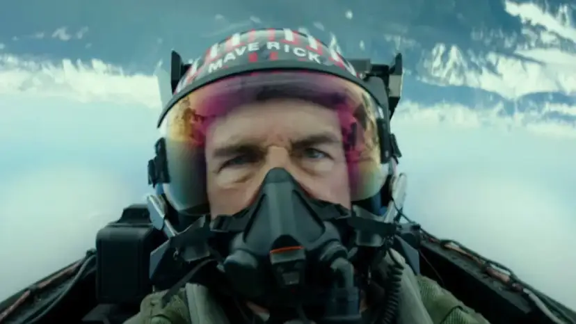 Tom Cruise jako Maverick w hełmie z napisem "MAVERICK" w filmie Top Gun: Maverick. Intensywne spojrzenie pilota w kokpicie myśliwca.