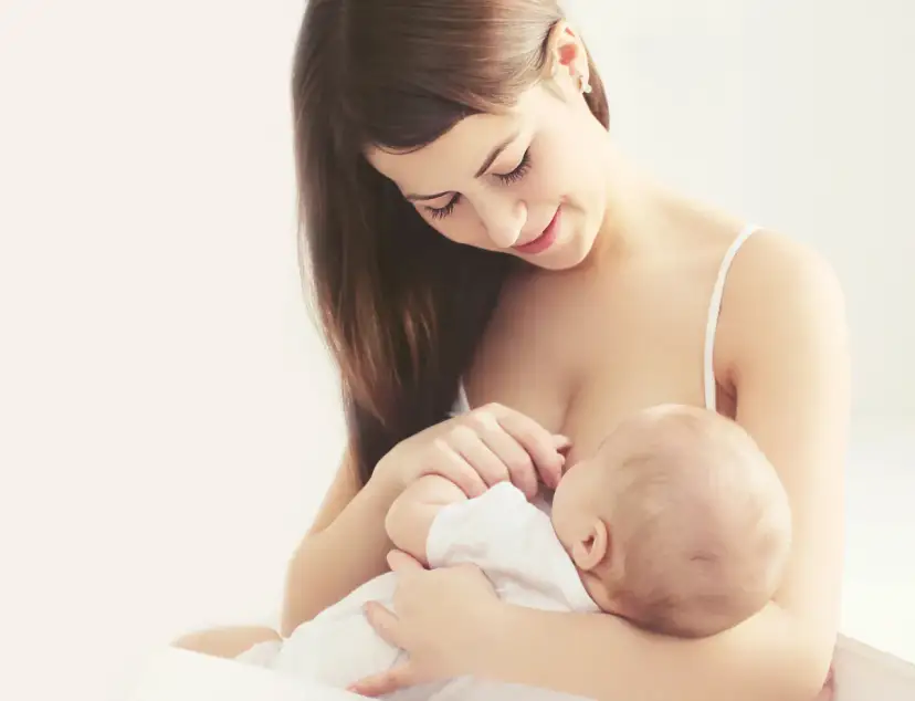 Uśmiechnięta mama karmi piersią dziecko, moment kiedy stabilizacja laktacji przynosi spokój i bliskość.