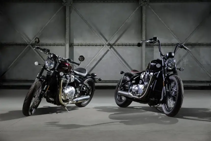 Dwa motocykle Triumph Bonneville Bobber w ciemnych kolorach, stojące obok siebie w industrialnym wnętrzu.