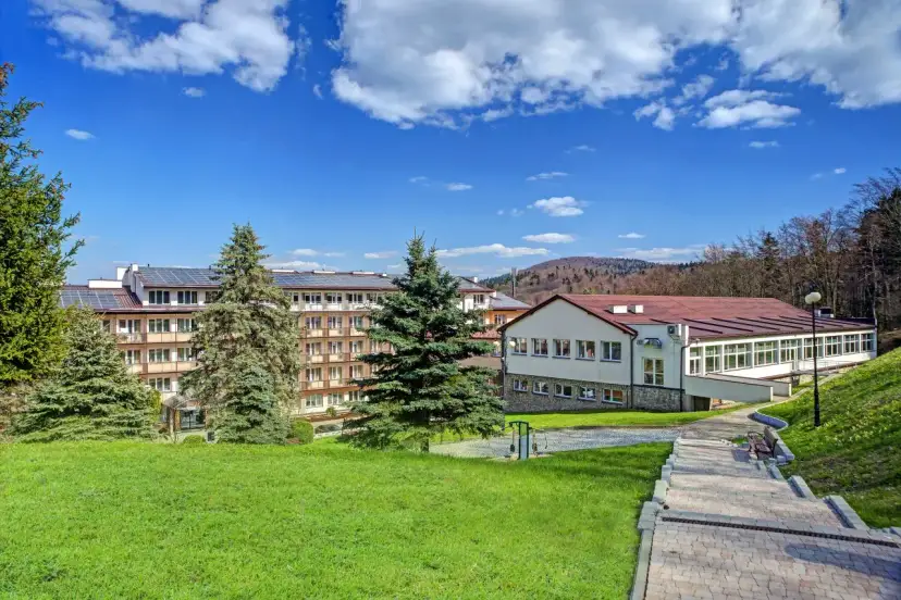 Górnicze sanatorium z panelami słonecznymi na dachu, otoczone zielenią. Miejsce odpoczynku dla każdego górnika.