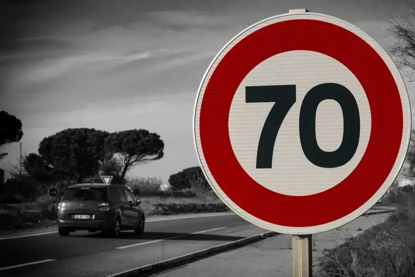 Znak drogowy ograniczający prędkość do 70 km/h, samochód na drodze.