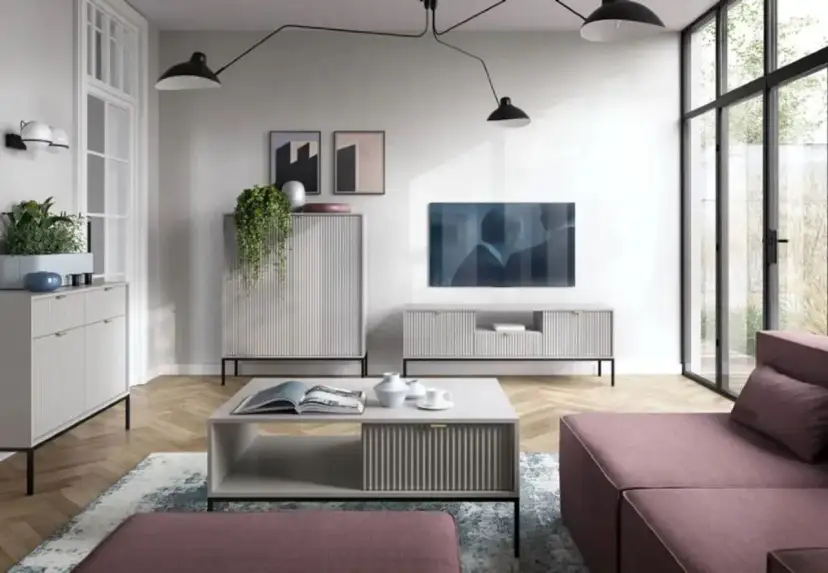 Nowoczesny salon z dużą **ścianą TV**, minimalistycznymi meblami i wygodną, różową sofą.