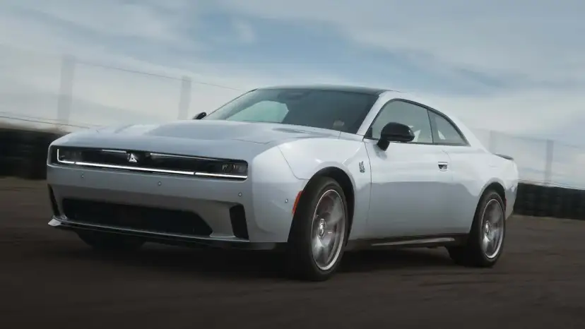 Biały Dodge Challenger Hellcat pędzi po torze wyścigowym, jego sylwetka jest dynamiczna i agresywna.