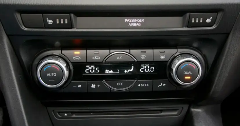 Panel sterowania klimatyzacją w samochodzie, z pokrętłami AUTO i DUAL, wyświetlaczem temperatury 20.5°C i ikonami nawiewu. Idealny do ozonowania klimatyzacji.